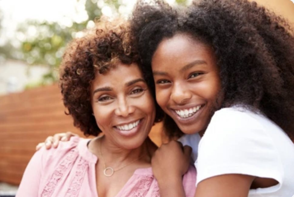 A woman and her daughter smiling for the camera.