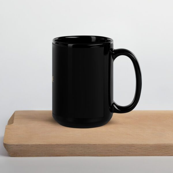 A black coffee mug sitting on top of a wooden table.