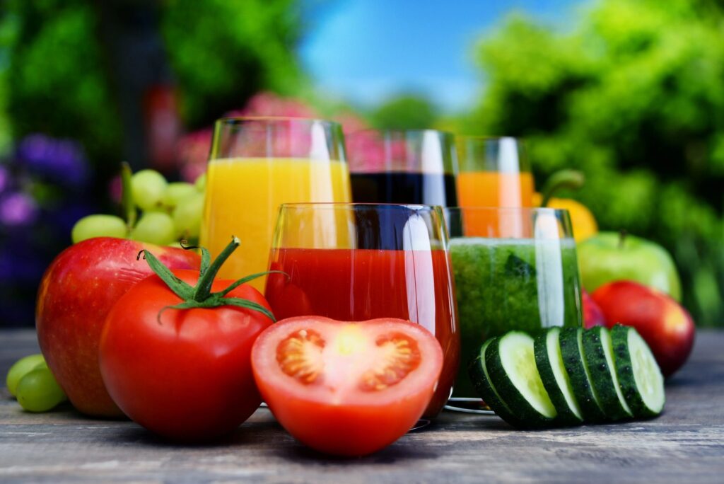 A table with several glasses of juice and vegetables.